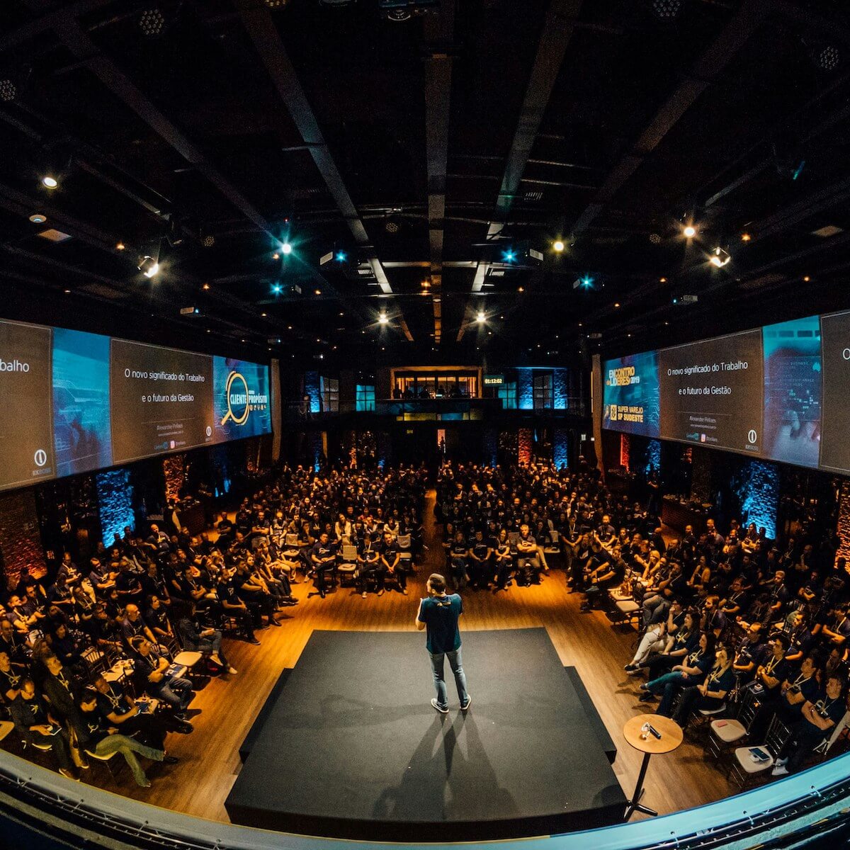 Audience at a marketing conference with speaker and presentation screens.