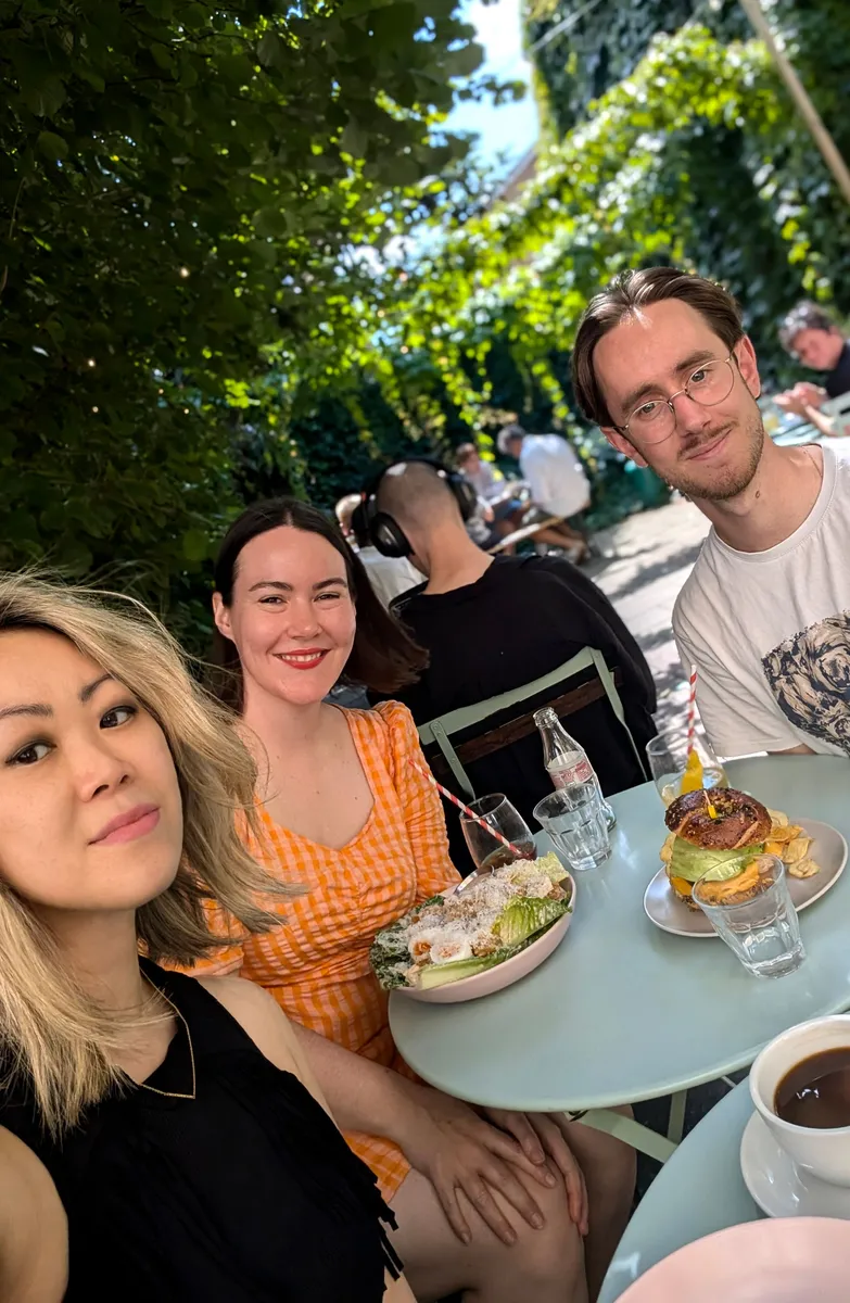 Three people dining outdoors in a lush, ivy-covered garden setting at a Creative Lunch Club meetup in London.