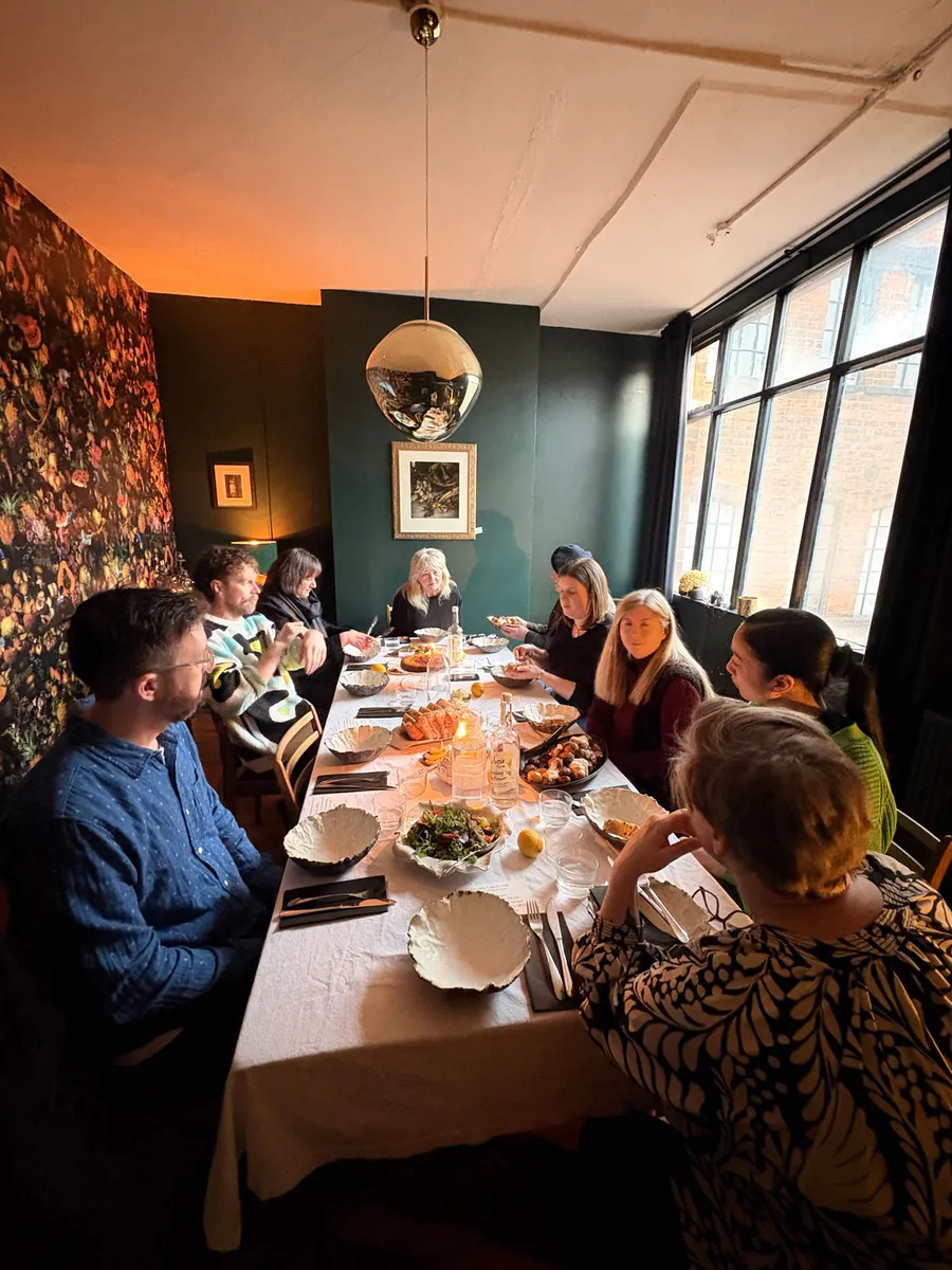 Group of creative professionals dining together at a Creative Lunch Club meetup in Birmingham, seated around a long table with food and drinks.