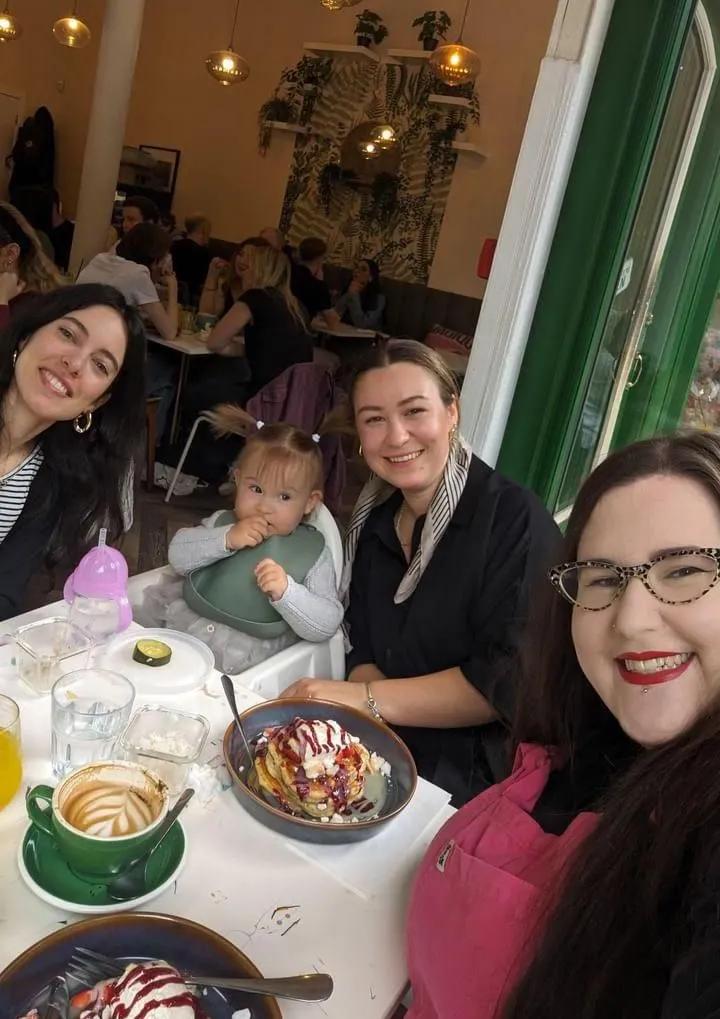 Four women smiling at a cafe table with food and drinks during a Creative Lunch Club meetup in Glasgow.
